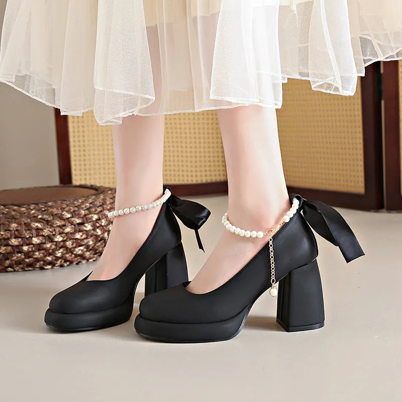 Women's beige Mary Jane shoes with chunky low heel, pearl decoration, and ankle strap buckle on a round toe.