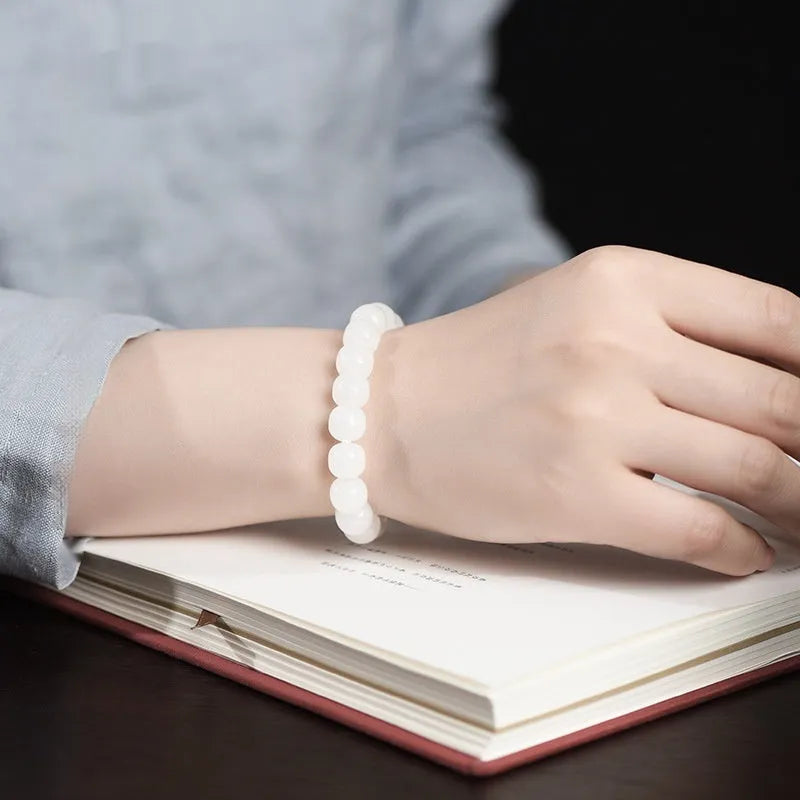 White Hetian jade barrel bead bracelet for men and women on a plain background.
