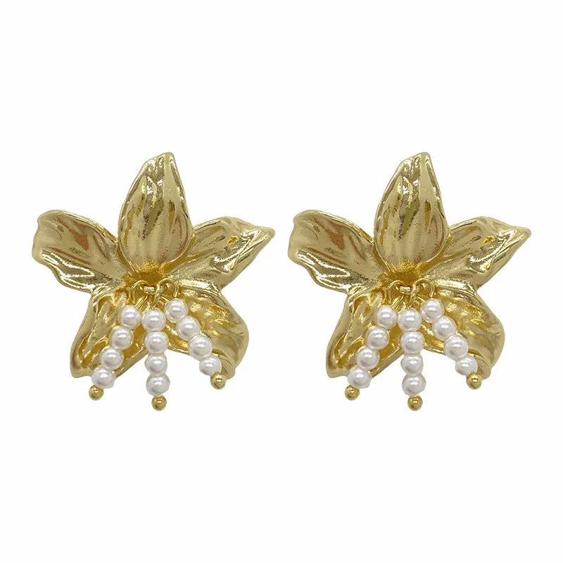 A pair of exaggerated gold metal flower earrings with pearl centres, showing a niche floral jewellery design.