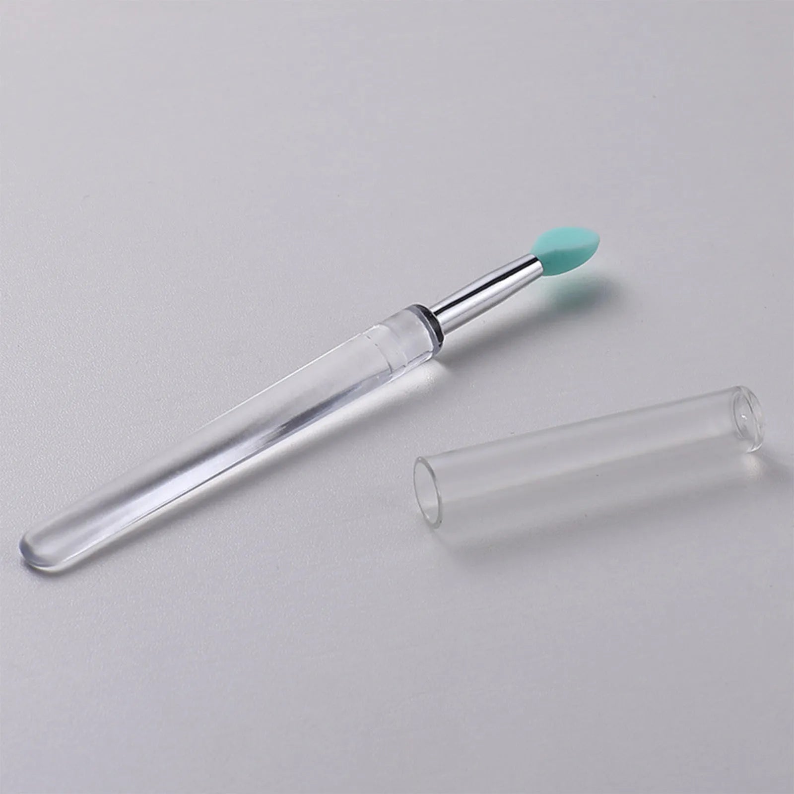 A reusable silicone lip brush with a handle and protective cap, shown in one of eight available colours.