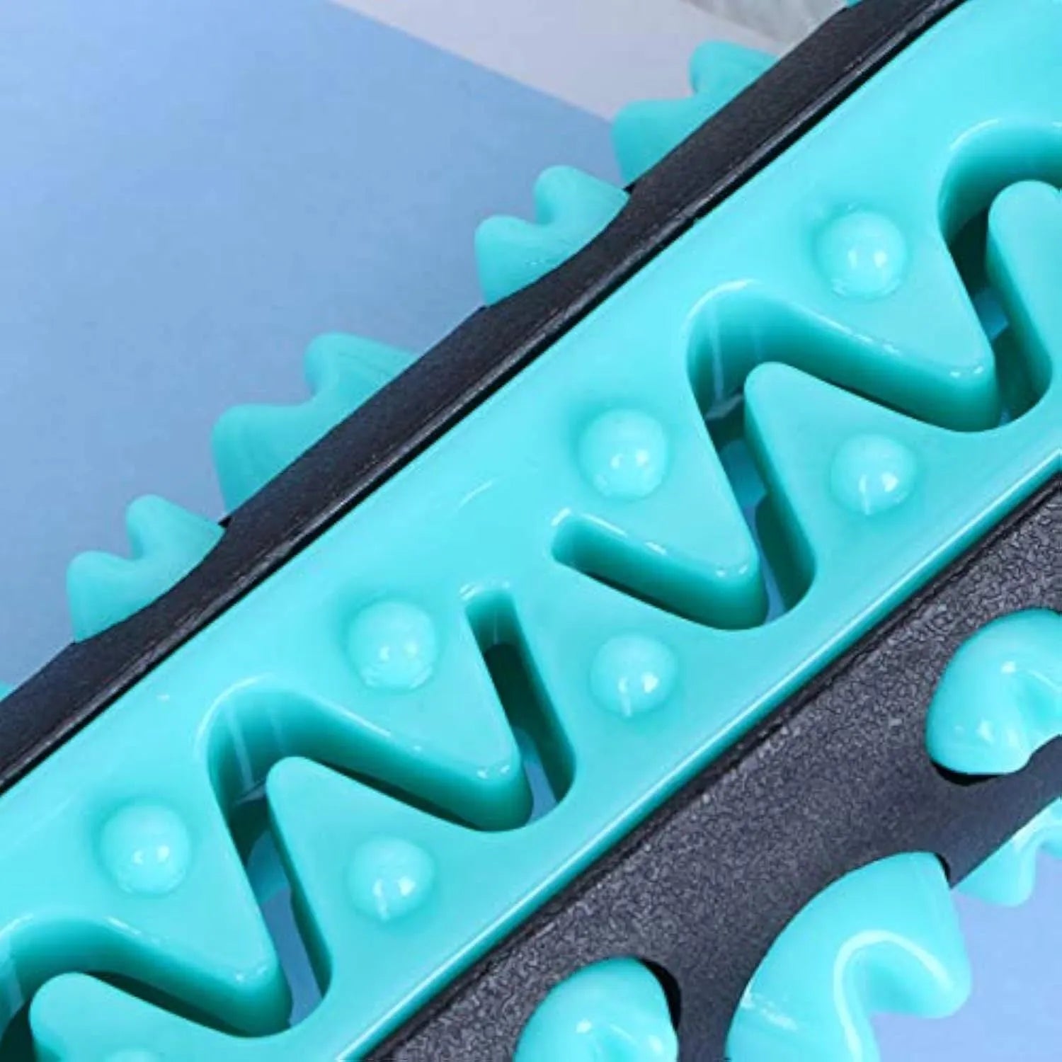 A blue natural rubber dog toothbrush chew toy with a textured surface, shown next to a green one.