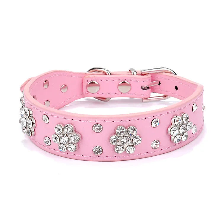 Close-up of a black PU leather dog collar with sparkling rhinestone flowers and a metal D-ring.