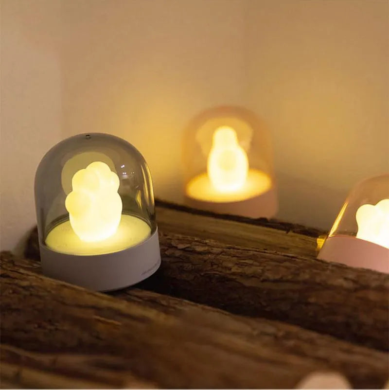Grey cat paw shaped USB rechargeable night light and music box with soft glowing light.