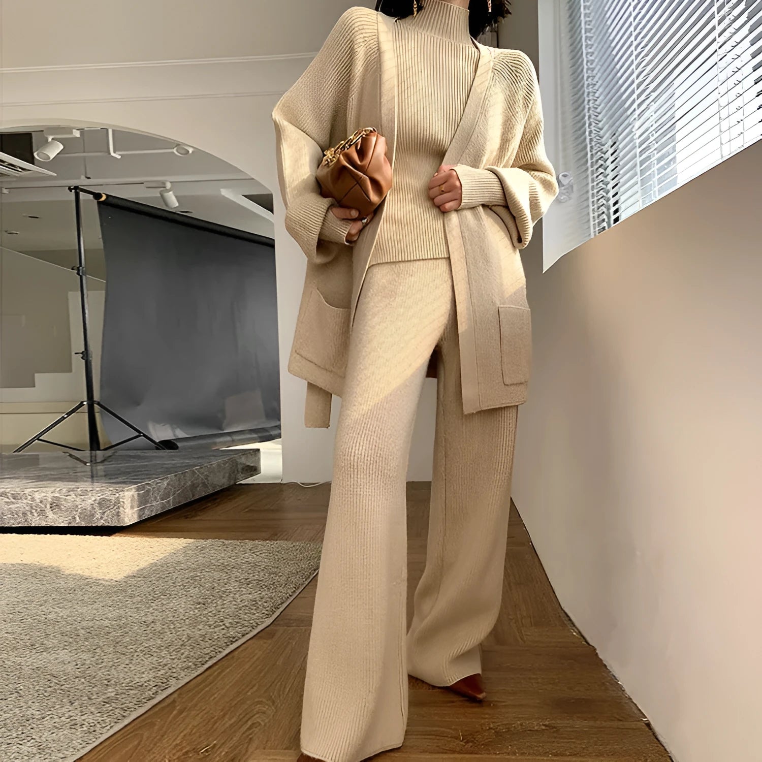 Women's apricot knitted three-piece set featuring a cardigan, wide-leg pants, and top with leather stitching details.