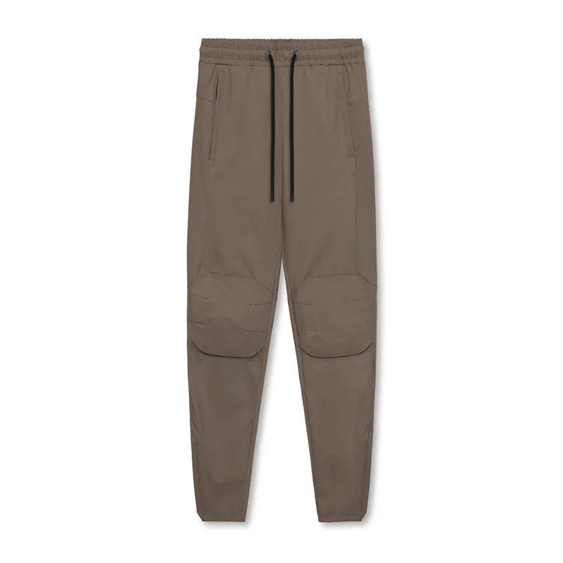 Men's loose grey fitness trousers with ankle ties on a gym floor.