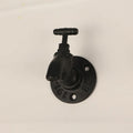 A polished metal wall hook in a water pipe design, shown in black, green, and red colour options.