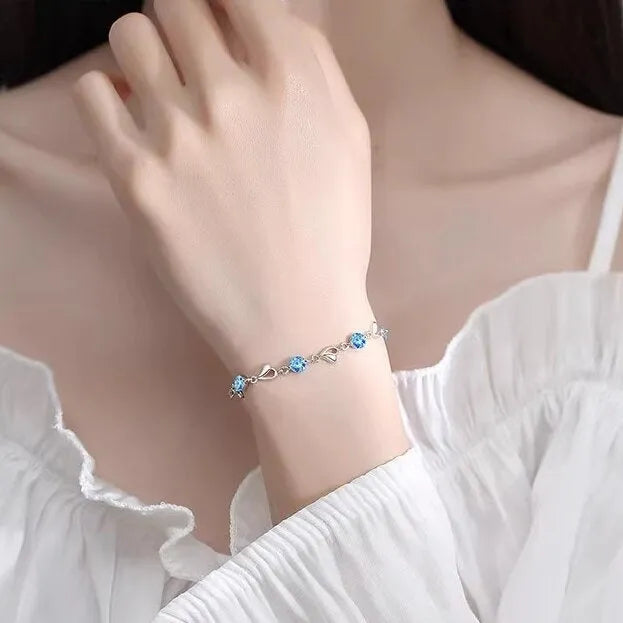Blue diamond heart-shaped necklace and matching bracelet set with gemstone inlays on a model
