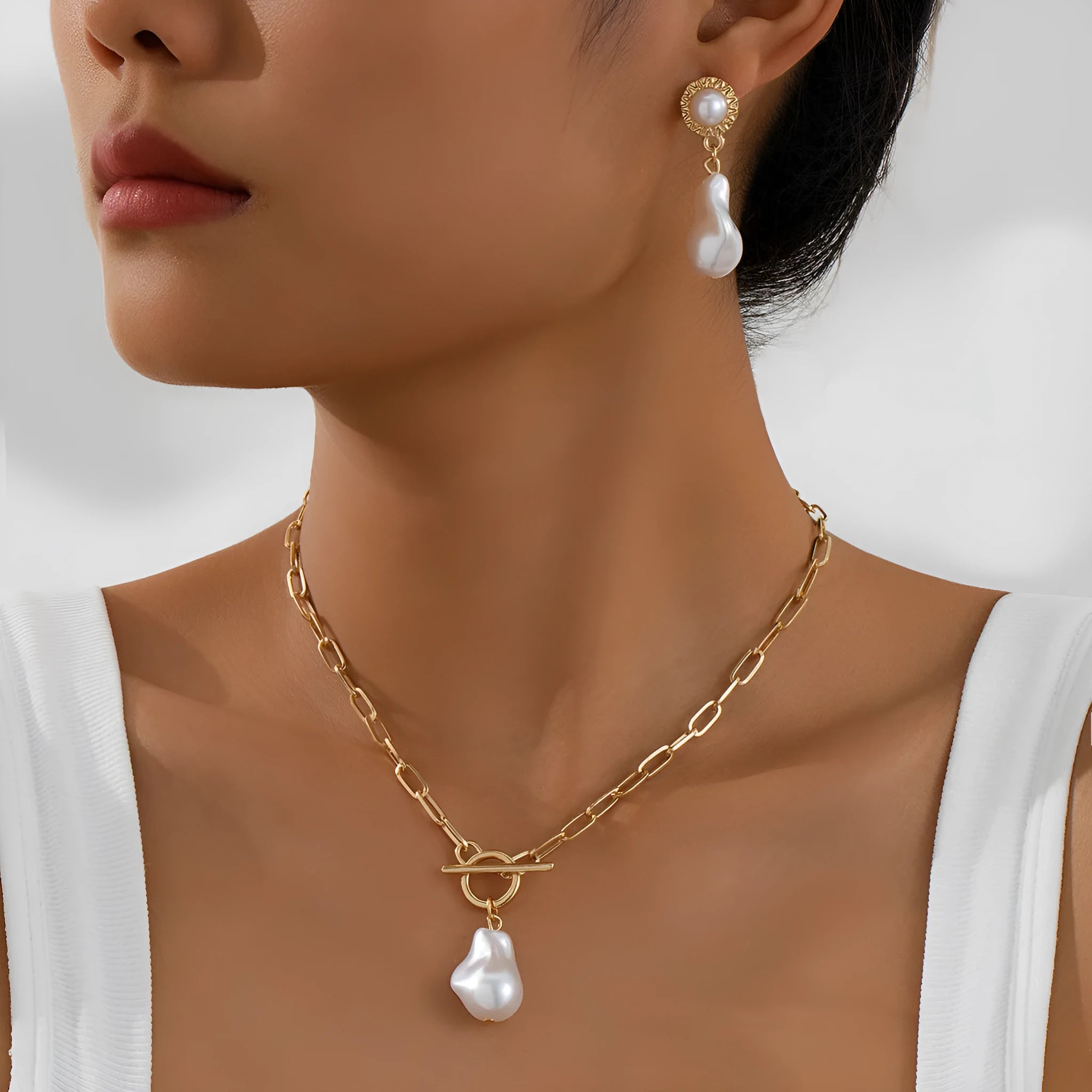 Gold-coloured retro baroque pearl pendant necklace and matching stud earrings set on a dark background.