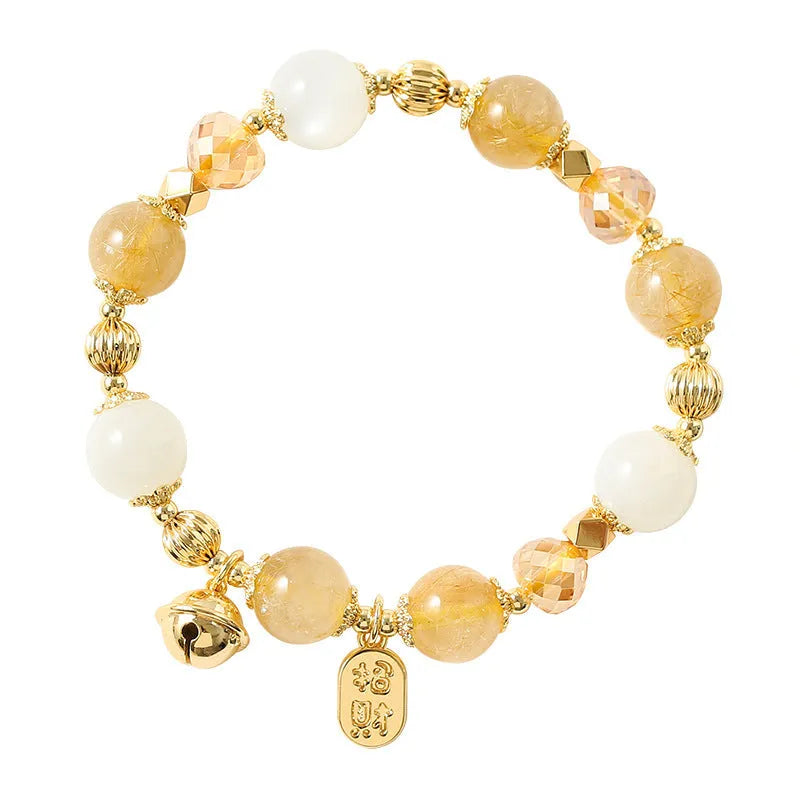 Gold rutilated quartz bracelet with bell charm on wrist