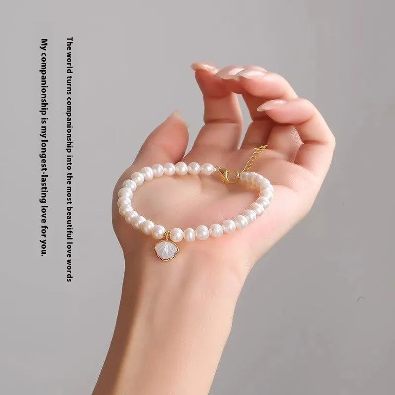 Women's freshwater pearl fan bracelet with alloy shell on wrist, showing elastic and chain closure options.