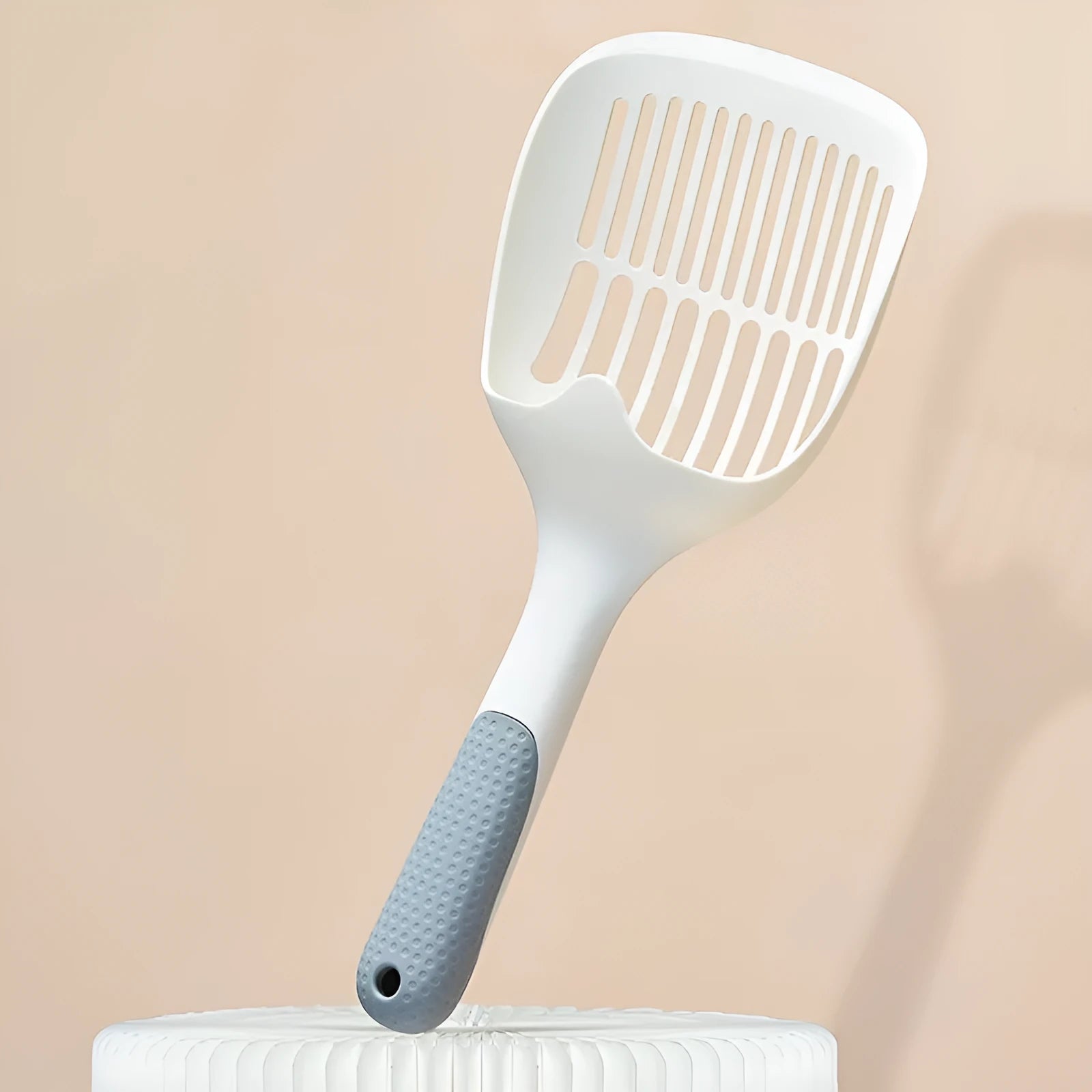 White plastic cat litter scoop with storage base on a clean surface