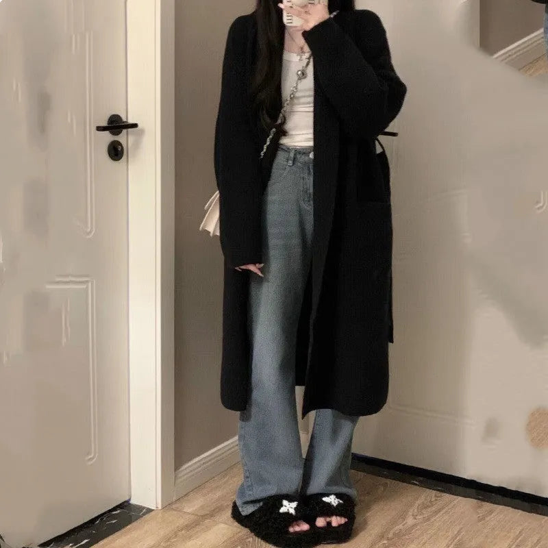 Loose black knitted women's cardigan with a 3D pattern, shown open over a white top.