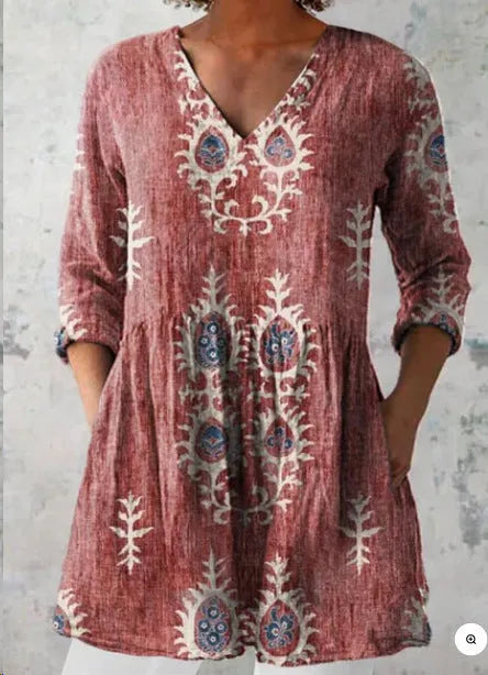 A woman wearing a printed, loose-fitting dress with a wide waist and three-quarter length sleeves.