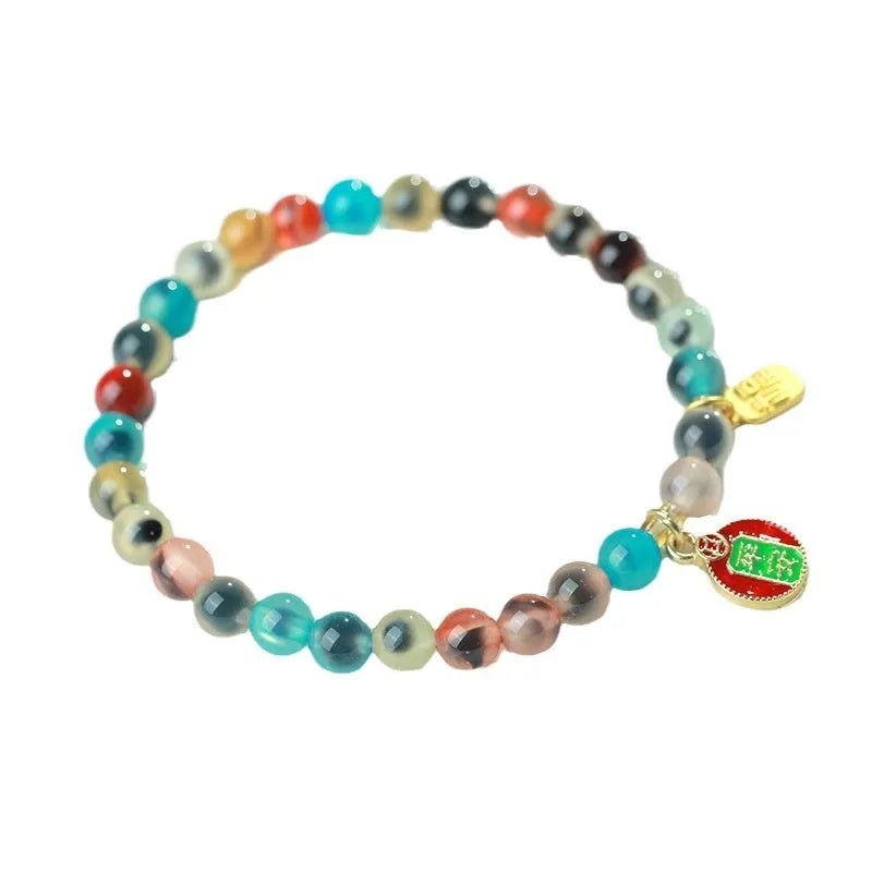 Close-up of a women's snake chain bracelet with colourful agate hearts and detailed copper coins.