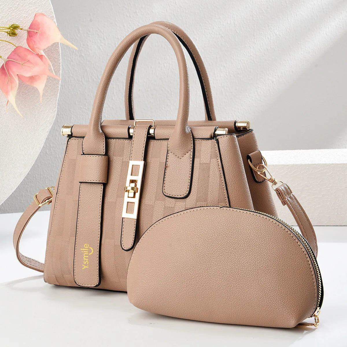 A pair of round black and light khaki PU leather crossbody bags with adjustable straps.