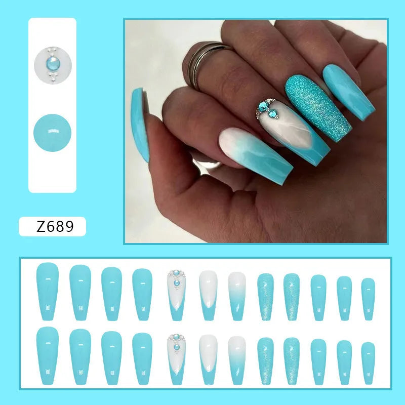 Long ballet shaped artificial nail patches with blue diamond glitter on a solid colour background, shown with a bottle of nail glue.
