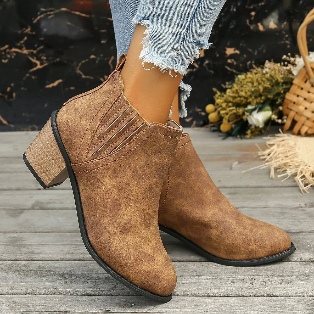 Black pointed toe ankle boots with a thick square low heel on a woman's foot.