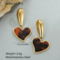A pair of gold-coloured geometric earrings with a heart shape and a floral design on a white background.