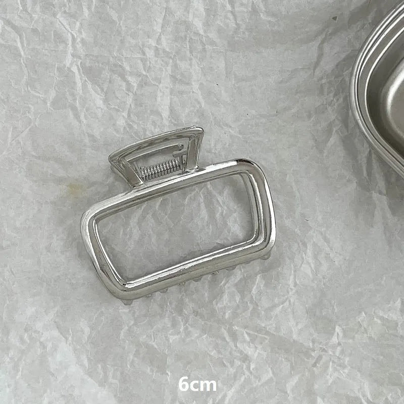 Silver metal hair claw clip assortment showing bows, waves, pearl designs, and geometric shapes from 4cm to 13.5cm