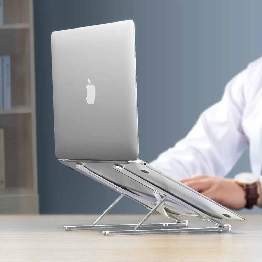 Silver foldable aluminium laptop stand holding a MacBook at an angle, shown next to a backpack.