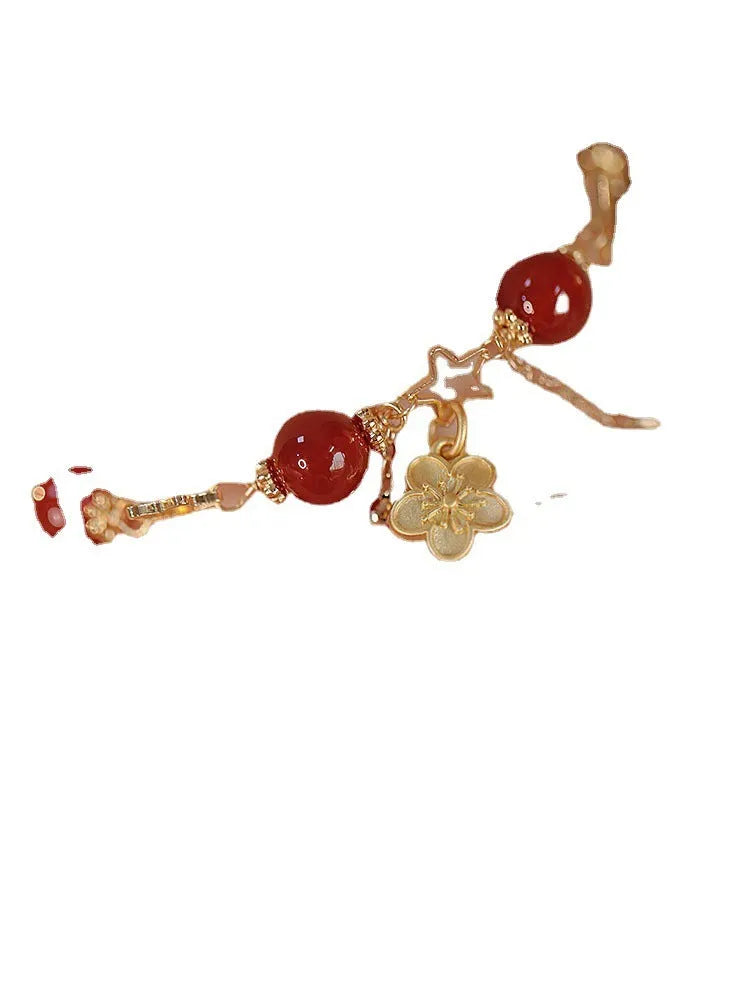 Red agate double layer bracelet with floral and peach blossom charms on a wrist.