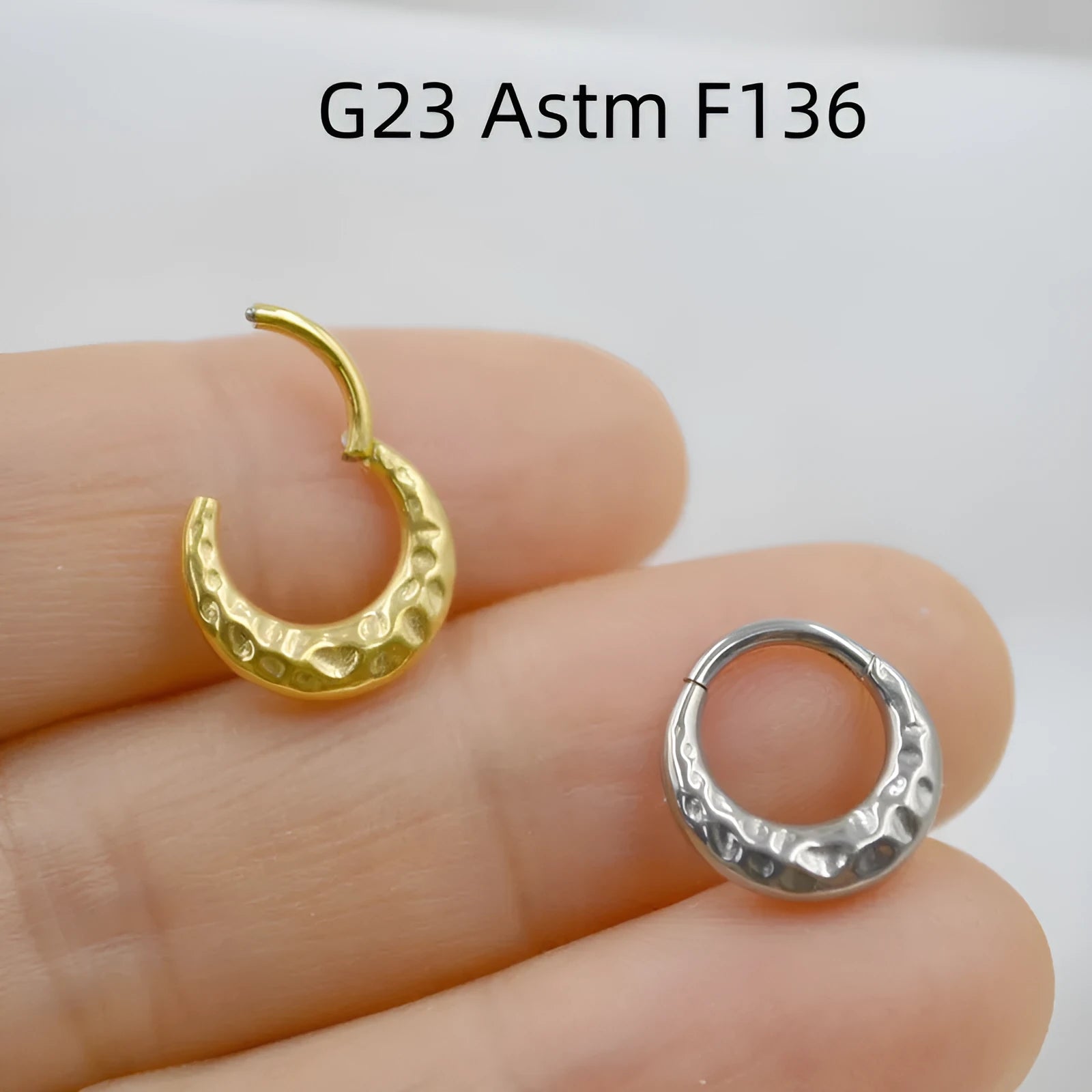 Titanium alloy concave-convex nose ring in gold and silver finishes showing surface texture detail