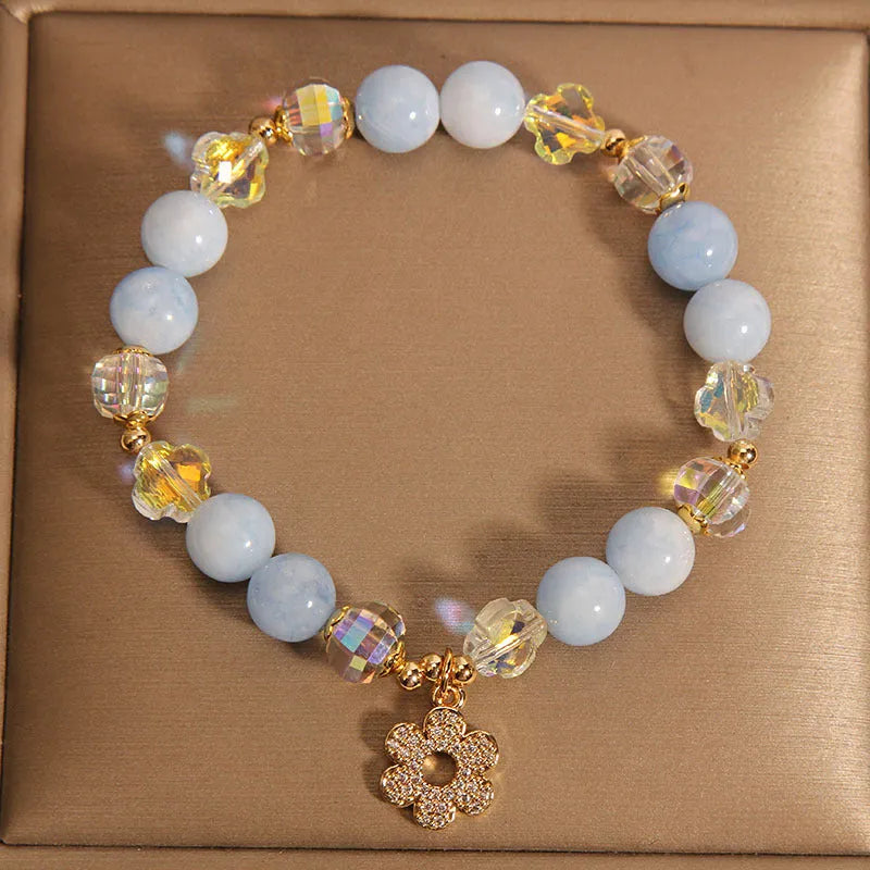 Women's aquamarine crystal four-leaf clover bracelet with pearl accents on a silver chain.