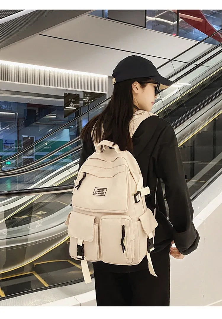 Black and white nylon student backpack with front 3D pockets, shown with laptop in compartment.