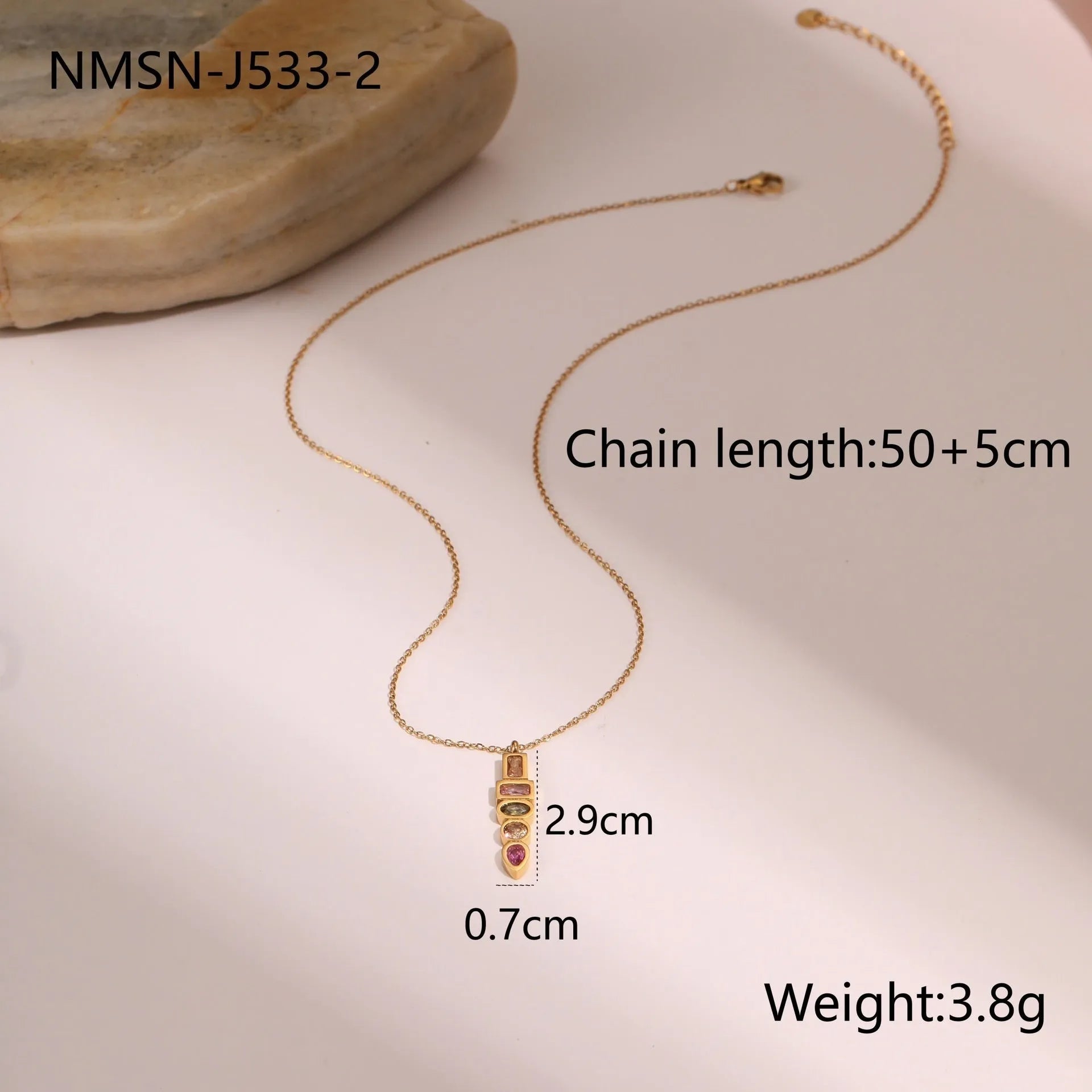 Geometric gold plated jewellery set with colour zircon necklace, ring, and earrings on a white background.