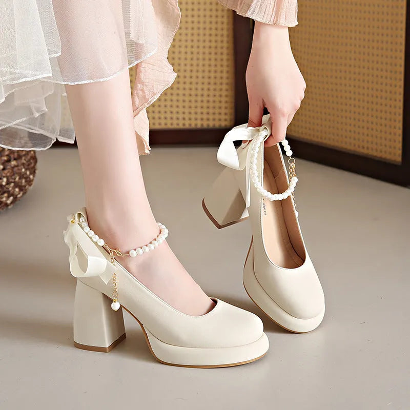 Women's beige Mary Jane shoes with chunky low heel, pearl decoration, and ankle strap buckle on a round toe.