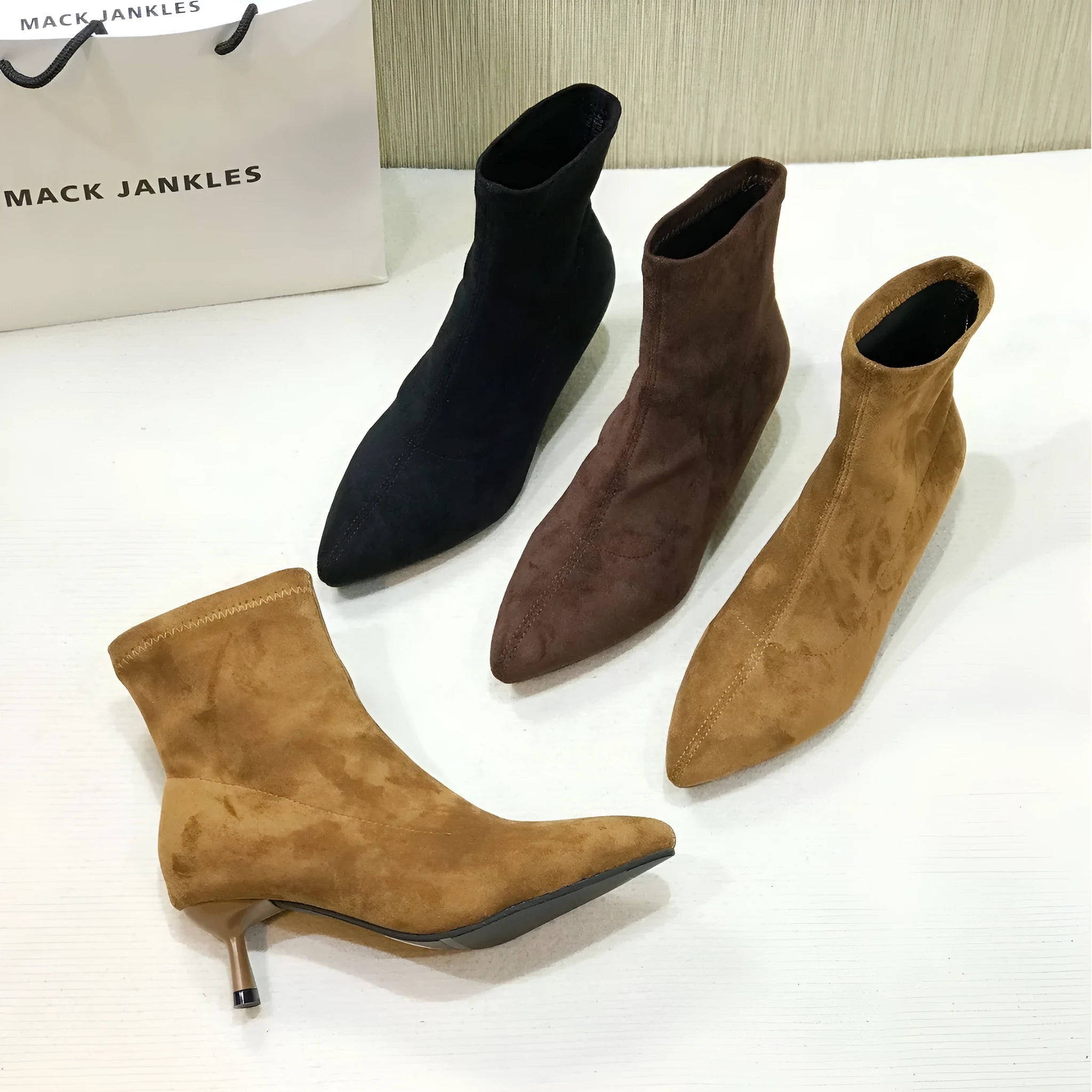 Black pointed toe women's ankle boots with a stiletto heel on a neutral background.