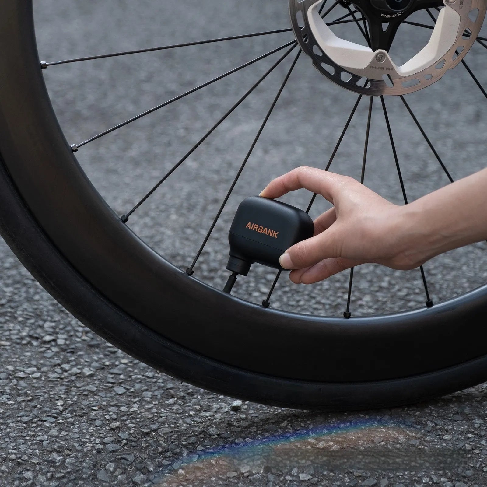 Black AS100 electric bike pump with USB cable and waterproof bag on a white background.