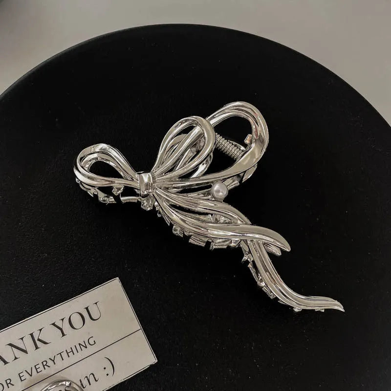 Silver metal hair claw clip assortment showing bows, waves, pearl designs, and geometric shapes from 4cm to 13.5cm