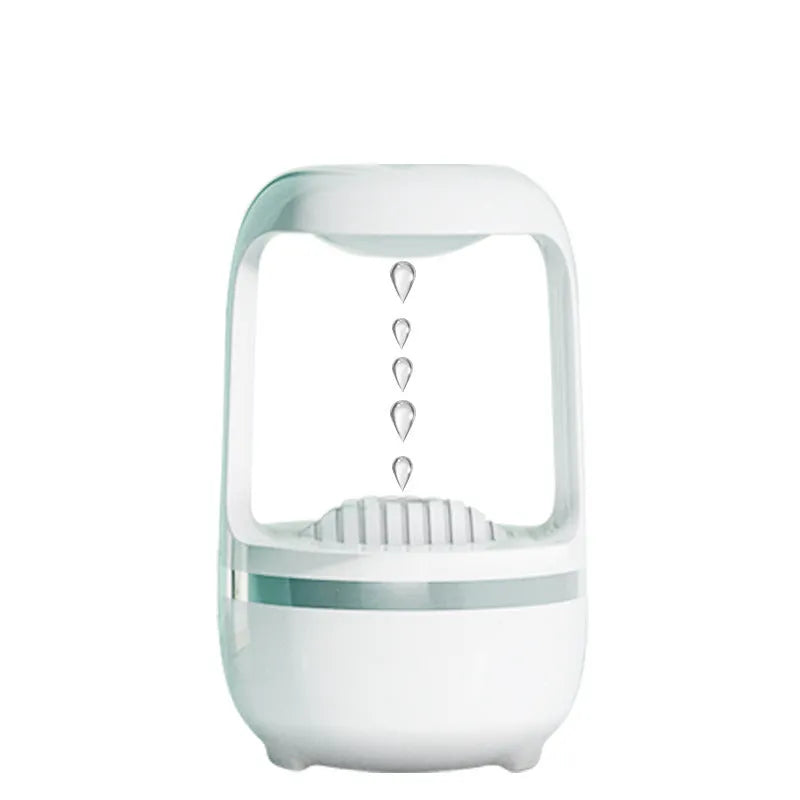 White anti-gravity humidifier on a desk showing water droplets in mid-air backflow, with USB cable.