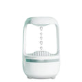 White anti-gravity humidifier on a desk showing water droplets in mid-air backflow, with USB cable.