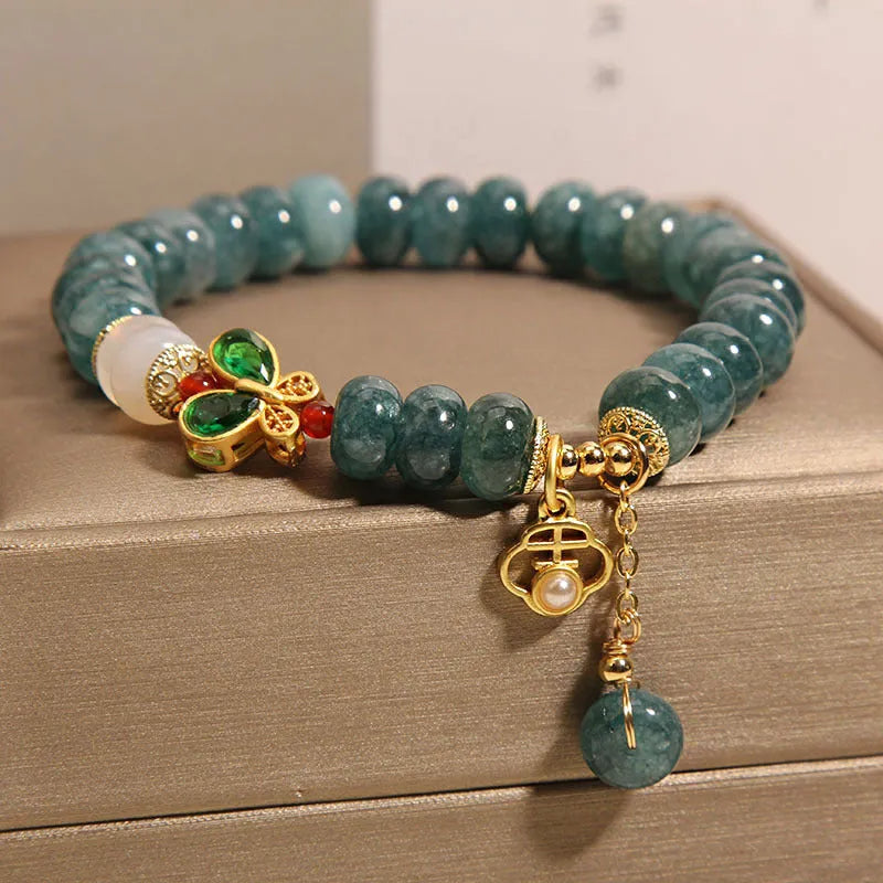 Blue water jade abacus bead bracelet with butterfly charm and white agate on an alloy band.