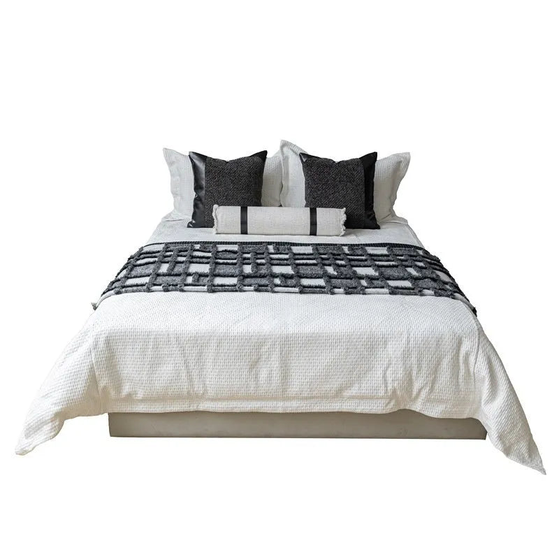Grey and white plaid polyester bed runner blanket set with matching pillowcase and round leather-look cushion on a bed