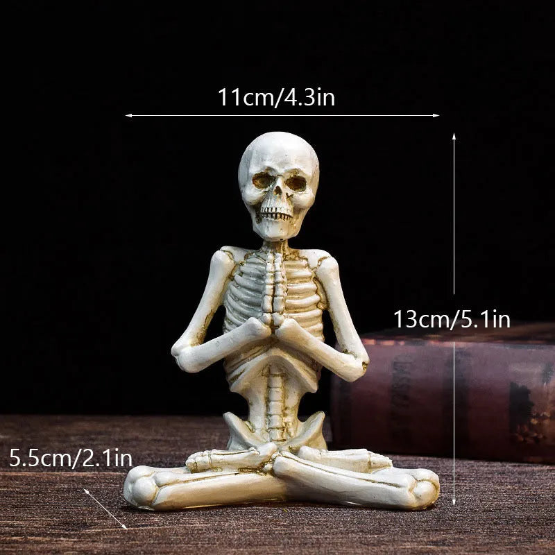 Detailed resin ornament of a yoga pose skeleton skull on a desktop, shown in black and white colour options.