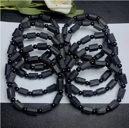 Black tourmaline rough stone bracelet with unpolished beads on a wrist.