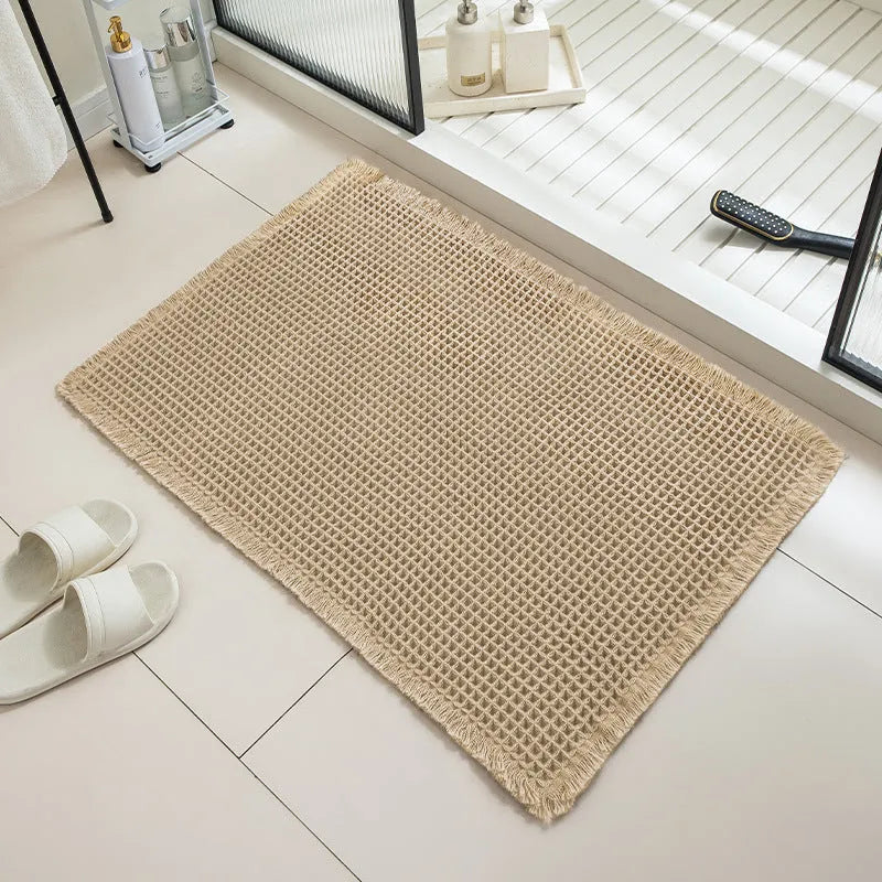 Modern checkered pattern absorbent non-slip bathroom floor mat in a neutral colour on tiled floor.