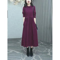 Purplish red plus size long sleeve dress for women with a long skirt, shown on a hanger.