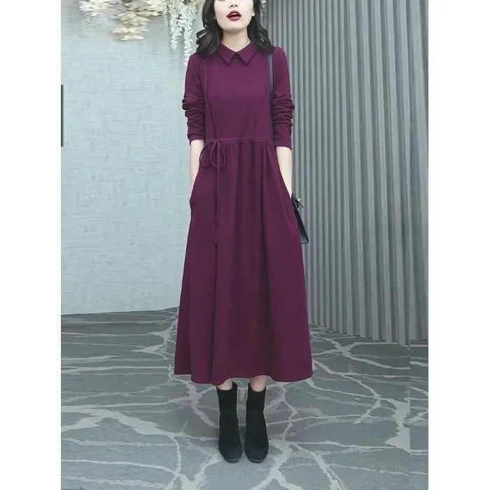 Purplish red plus size long sleeve dress for women with a long skirt, shown on a hanger.