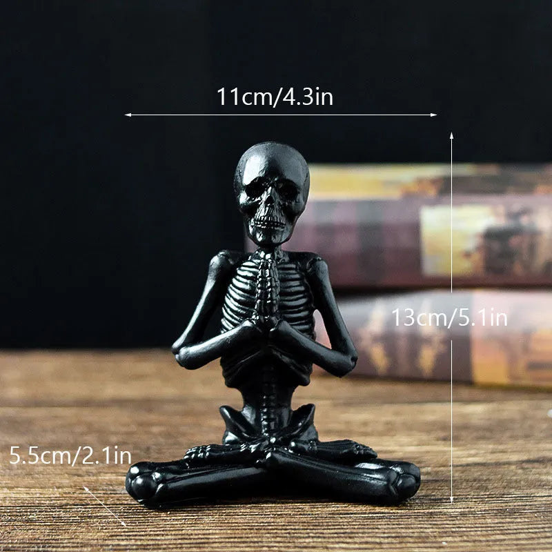 Detailed resin ornament of a yoga pose skeleton skull on a desktop, shown in black and white colour options.
