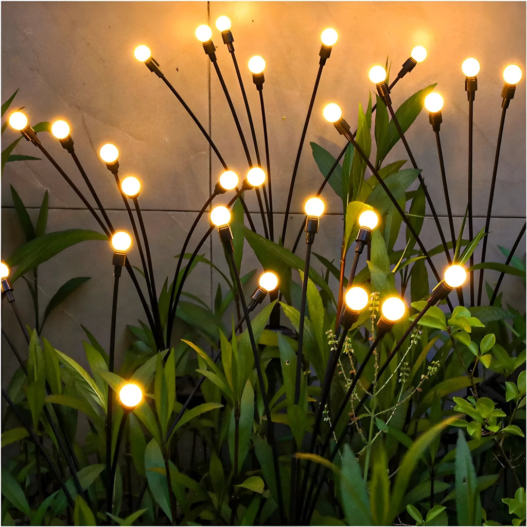 Solar-powered LED garden ground light with stainless steel spike inserted in lawn showing automatic dusk-to-dawn operation