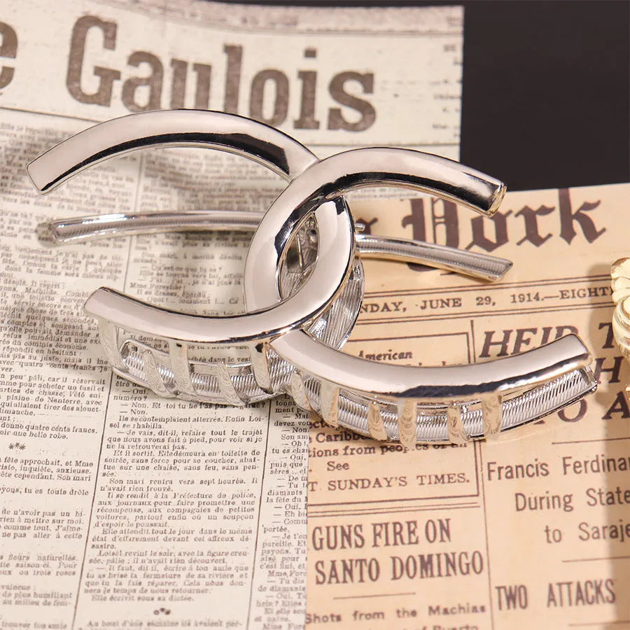 Silver metal hair claw clip assortment showing bows, waves, pearl designs, and geometric shapes from 4cm to 13.5cm