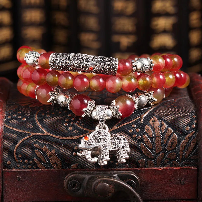 Natural watermelon crystal bracelet with a handmade Chinese knot closure, showing geometric beads.