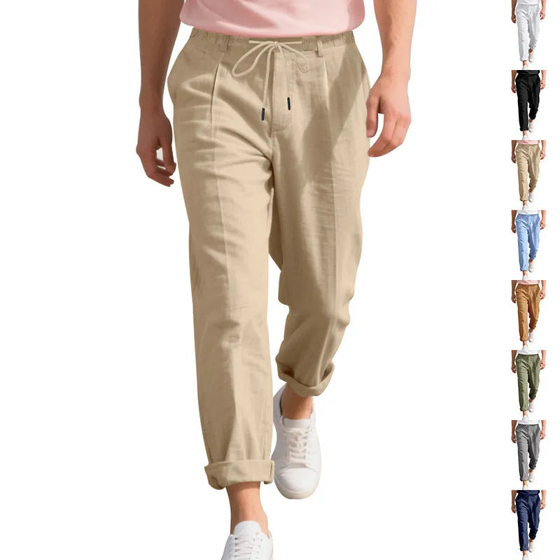 Men's straight leg linen trousers in light khaki colour with drawstring waist, laid flat.