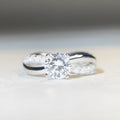 Geometric cross moissanite ring with winding twisted silver arms and four-claw setting