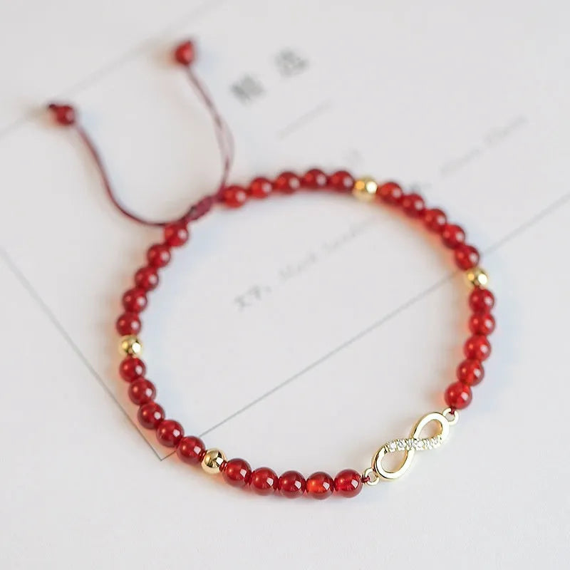 Hand-woven red agate bead bracelet with ethnic design on a wrist.