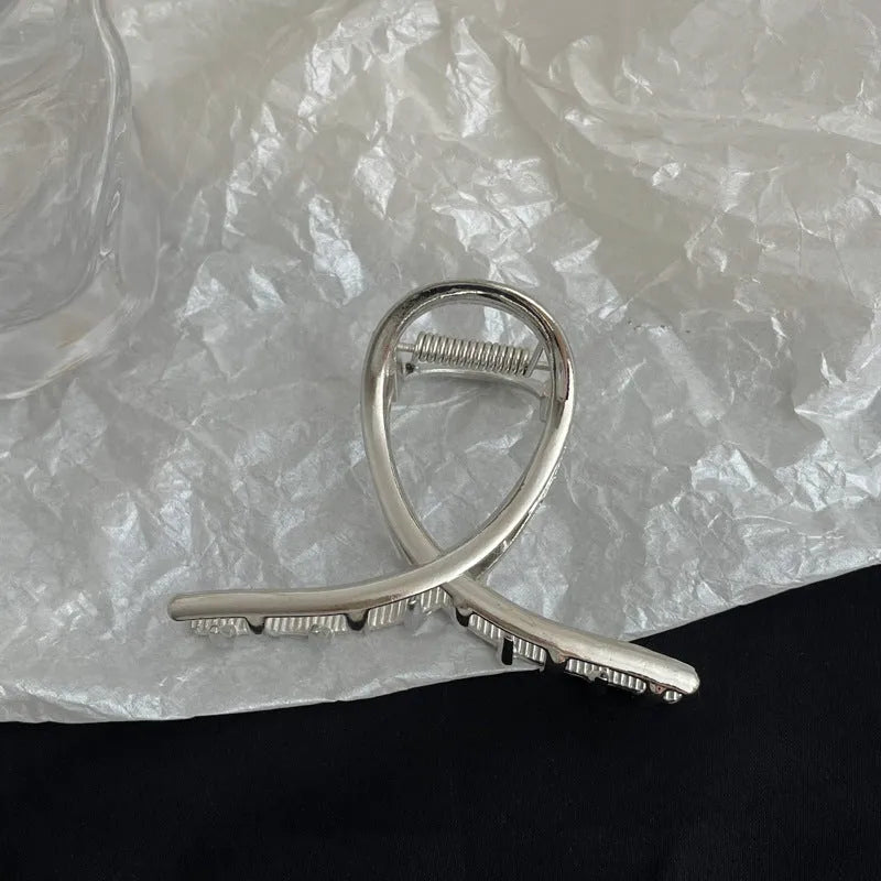 Silver metal hair claw clip assortment showing bows, waves, pearl designs, and geometric shapes from 4cm to 13.5cm
